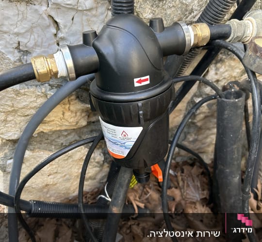 מסנן מים עם צינורות וחיבורים על קיר אבן